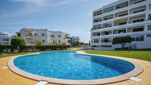A modern apartment complex with a circular swimming pool surrounded by a paved area.