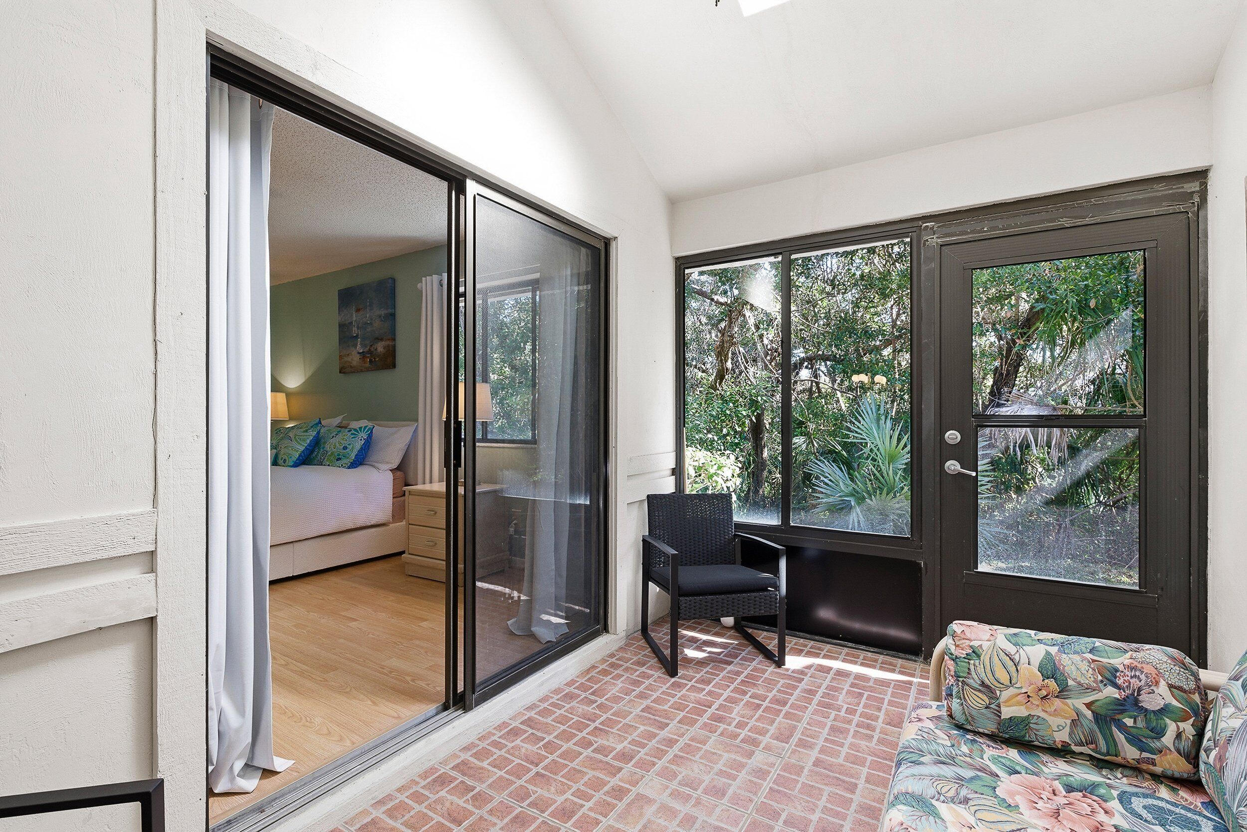 Une chambre dotée d’une porte-fenêtre coulissante donnant sur un balcon, d’un lit avec une table de chevet et d’une chaise.