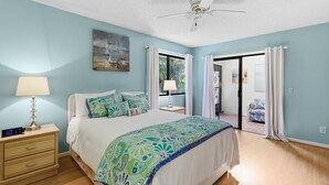 Un dormitorio con cama, mesita de noche, lámpara y ventilador de techo.