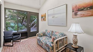 Una habitación con sofá, una silla, una lámpara y obras de arte en las paredes.