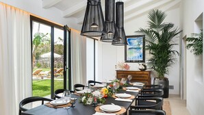 A dining area with a long table set for six, black chairs, and a large potted plant.