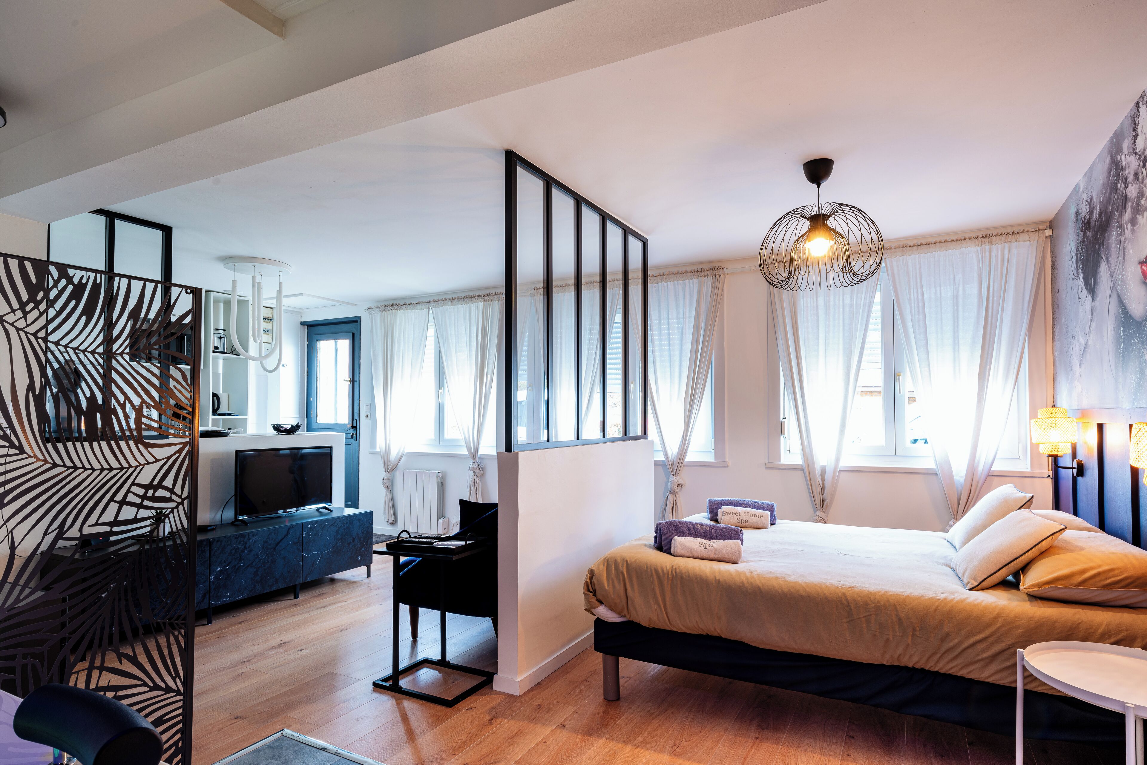 Ein modernes Hotelzimmer mit Bett, Schreibtisch, Fernseher und einem großen Fenster mit Vorhängen.