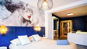 Ett modernt hotellrum med en stor säng, en blå sänggavel och en väggmålning.