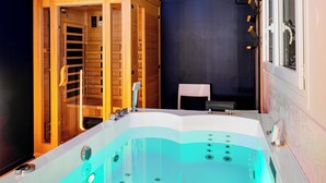 Ett spa-rum med ett bubbelbad, en träpanelad bastu och ett fönster med persienner.