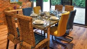Een eetgedeelte met rieten stoelen, een glazen tafel voor zes personen en uitzicht op groen.