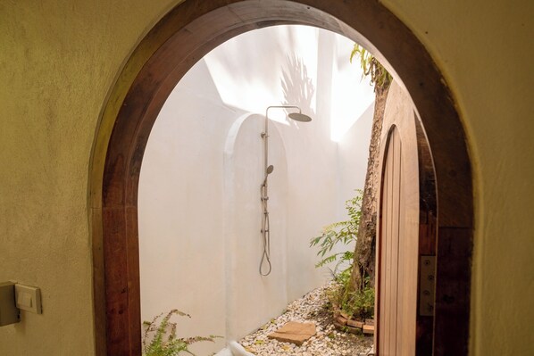 A narrow passageway with a shower, a wooden door, and a small garden area. - La Lanna Chiang Mai (Mae On)