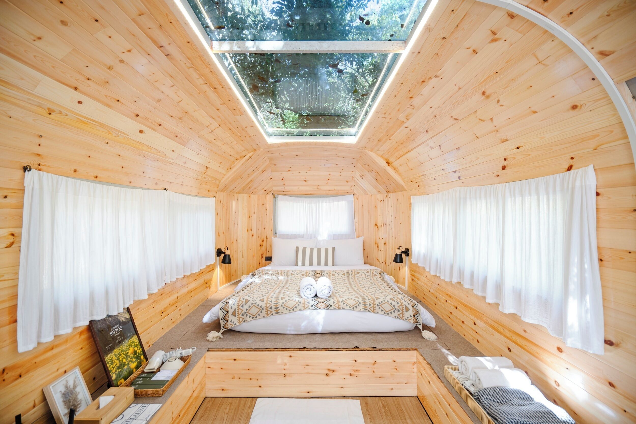 Una habitación de madera con tragaluces, una cama y una ventana.
