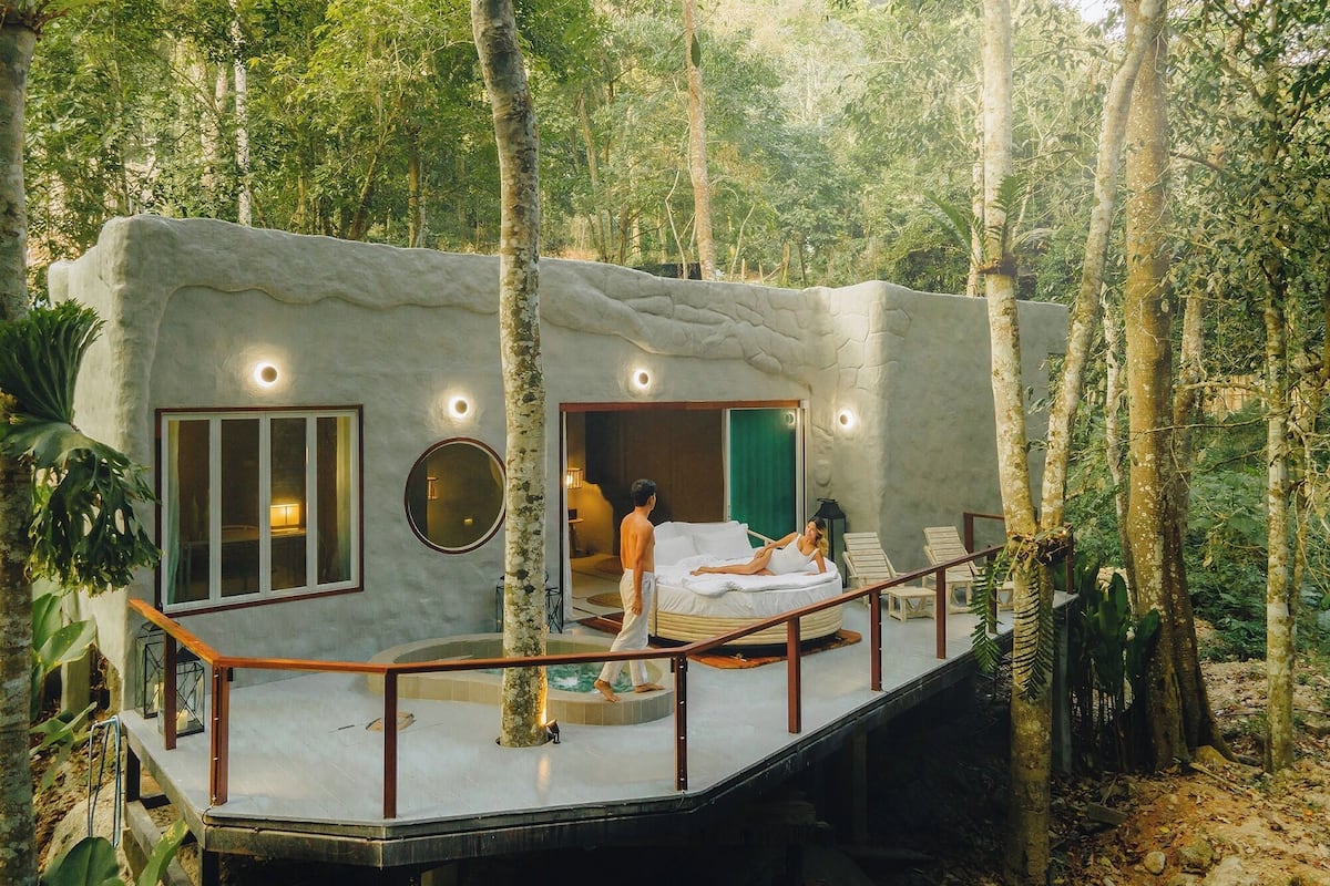 A treehouse with a single bed, a small window, and a balcony.