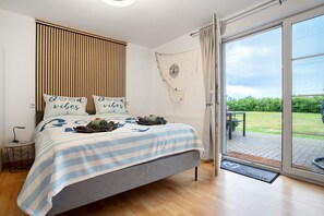 Une chambre à coucher comprenant un lit, une table de chevet, une fenêtre donnant sur un paysage agréable et une porte menant à un espace extérieur.