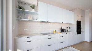 Una cucina moderna con mobili bianchi, un forno nero e una parete rivestita di piastrelle.
