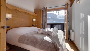 Een gezellig slaapkamer met een groot bed, een houten hoofdbord en uitzicht op een besneeuwde berg.