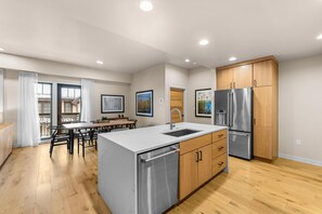 A modern kitchen with stainless steel appliances, wooden cabinets, and a marble countertop.