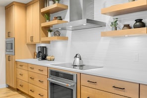 A modern kitchen with wooden cabinets, a stainless steel sink, and a built-in oven.