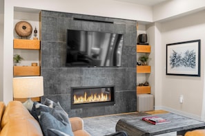 A modern living room with a fireplace, a flat-screen TV, and a cozy seating area.