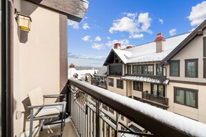 Een balkon met een metalen hekwerk met uitzicht op een woonwijk met sneeuwbedekte daken en huizen.
