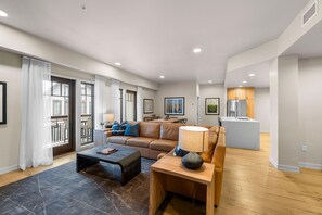 A spacious living room with a sofa, coffee table, and a dining area with a table and chairs. - Moose Chalet | Exclusive Tamarack Perks (Tamarack)