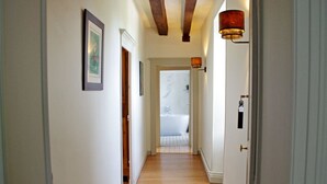 A hallway with wooden flooring, white walls, and a door leading to a bathroom with a bathtub. - Elegant B&B in La Ménitré with heated pool and wifi (La Ménitré)