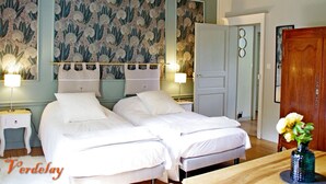 A bedroom with two beds, a wooden ceiling, a wall with floral wallpaper, and a wooden wardrobe. - Elegant B&B in La Ménitré with heated pool and wifi (La Ménitré)