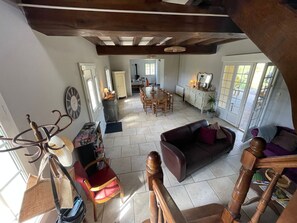 Un espacio habitable amplio con una mesa de comedor, un sofá y una escalera con barandillas de madera.