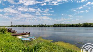 Un lac paisible, avec des bateaux amarrés sur la rive, entouré de verdure et d’arbres.