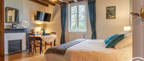 Un dormitorio con cama, escritorio, silla, televisor y ventana con cortinas.