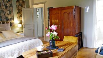 Quarto de hotel com cama, mesa de madeira com um vaso de flores, uma cadeira e um guarda-roupa.