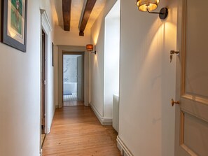 A hallway with wooden flooring, a radiator, and a door with a brass handle. - Elegant B&B near Loire with park and pool (La Ménitré)