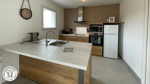 Una cocina moderna con una isla central, horno empotrado, microondas y refrigerador.