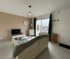 A modern living room with a sofa, TV, and a dining area with a table and chairs.