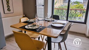 A dining area with a table set for four, a refrigerator, and a view of buildings through a window. - Cozy apartment in Laval, parking included, for 4 people (Laval)
