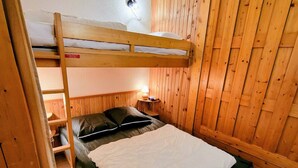 A bunk bed with a wooden headboard, a bedside table with a lamp, and a window with wooden shutters. - Apartment 5 pers, Bright, Wifi, Pets allowed (Les Arcs 1800)