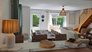 Ein modernes Wohnzimmer mit Essbereich, einer Treppe und Blick ins Freie.
