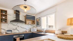 Eine moderne Küche mit Marmorfliesenspiegel, dunklen Schränken und einer Holztheke mit Schüsseln.