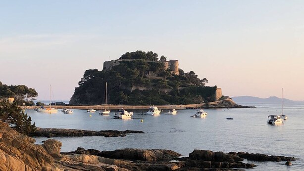 A coastal scene with a prominent rocky outcrop and a castle on a hill.