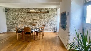 Un comedor con pared de piedra, mesa de madera y sillas.