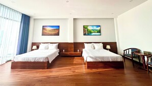 Ein Hotelzimmer mit zwei Betten, Holzboden und zwei Landschaftsbildern an den Wänden.