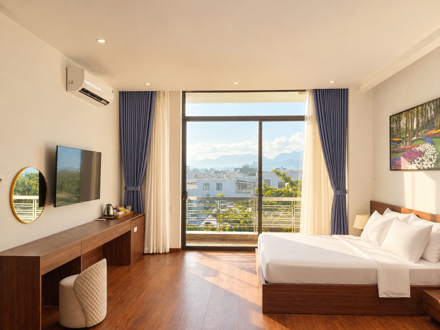 Habitación de hotel con cama, escritorio, televisor, ventana grande con cortinas y un cuadro en la pared.
