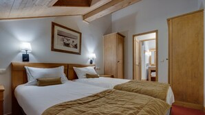 A hotel room with two beds, wooden headboards, a framed picture on the wall, and a wardrobe. - Arc 1950 - 3-Room Apartment, 67sqm, 6 pax (Les Arcs 1950)