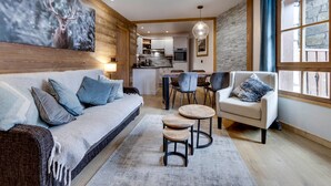 A modern living room with a sofa, armchairs, and a coffee table. A kitchen is visible in the background. - Arc 1950 - Apartment 4 people, ski-in/ski-out, wellness included (Les Arcs 1950)
