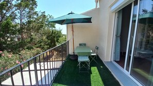 A small outdoor patio with a table and chairs, a green umbrella, and a sign that reads "Yella".