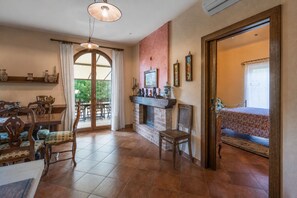 A dining area with a table and chairs, a fireplace, and a view through a glass door.