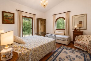 A bedroom with two beds, a nightstand, a dresser, a mirror, and a window with curtains.