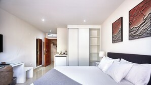 Ett modernt hotellrum med en stor säng, ett skrivbord och en garderob.