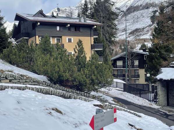 A multi-story building with a stone retaining wall and snow-covered ground.