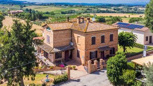 A traditional brick building with a tiled roof, a small balcony, and a solar panel on the roof. - Nice apartment for 3 guests with A/C, WIFI, patio and pets allowed (Montepulciano)