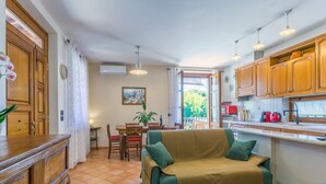 A cozy kitchen with wooden cabinets, a dining area with a table and chairs, and a sofa in the center. - Nice apartment for 3 guests with A/C, WIFI, patio and pets allowed (Montepulciano)