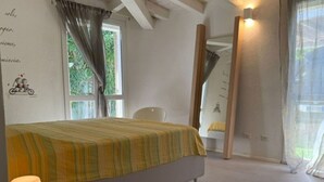 A bedroom with a bed, a chair, a lamp, and a window. - Beautiful private villa for 11 guests with WIFI, A/C, TV, patio and panoramic view (Villasimius)