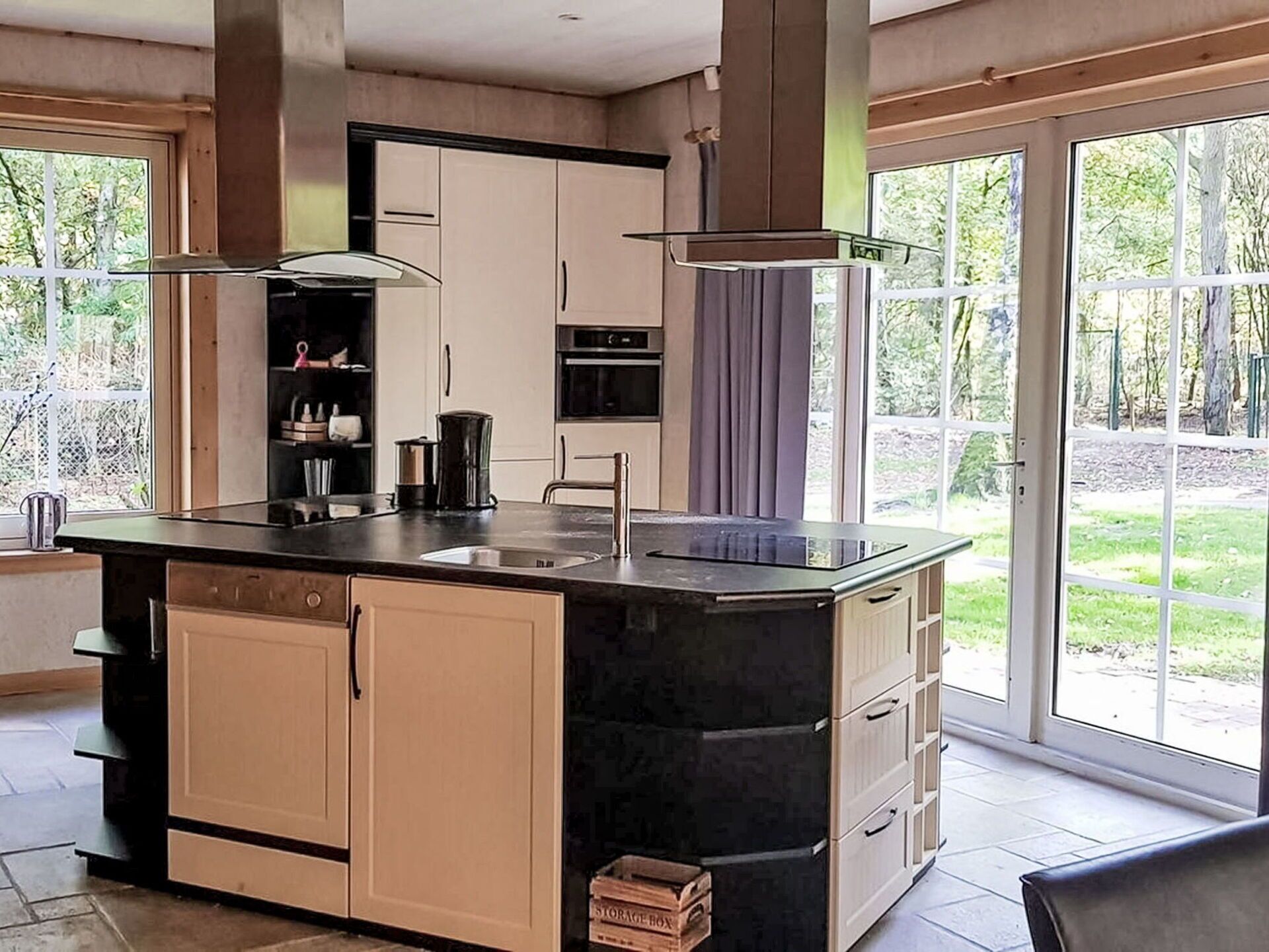 Une cuisine moderne dotée d’un îlot central, de meubles de rangement intégrés et d’une grande fenêtre offrant une vue sur l’extérieur.