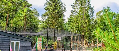 A fenced playground area with climbing structures and a building with a door and windows.