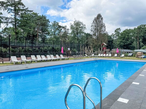 A swimming pool with lounge chairs and a wooden deck area. - Stunning private villa for 10 guests with WIFI, pool, TV and terrace (Apeldoorn)